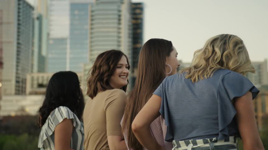 Women dressed in business attire walking together laughing and smiling near a city