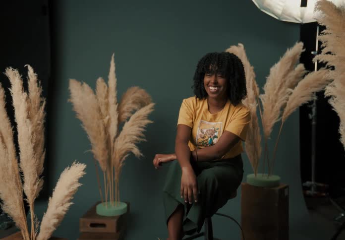 A woman sitting in a photo studio on a stool laughing and smiling