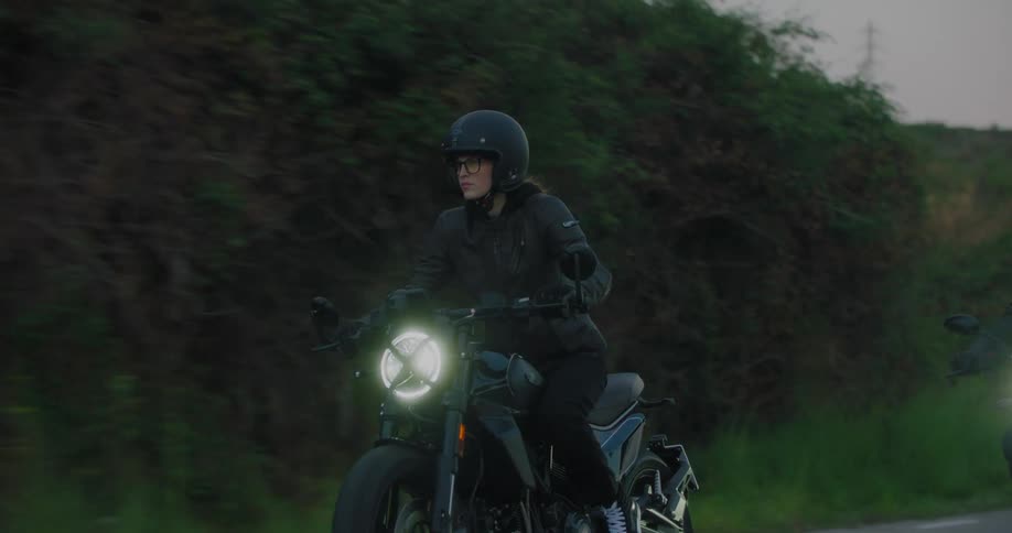 A woman riding a motorcycle driving it up a road with two people on motorcycles behind her