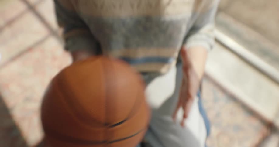 Woman sitting on a patio smiles while passing the basketball between her hands