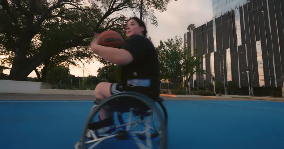 A girl in a wheelchair is playing basketball