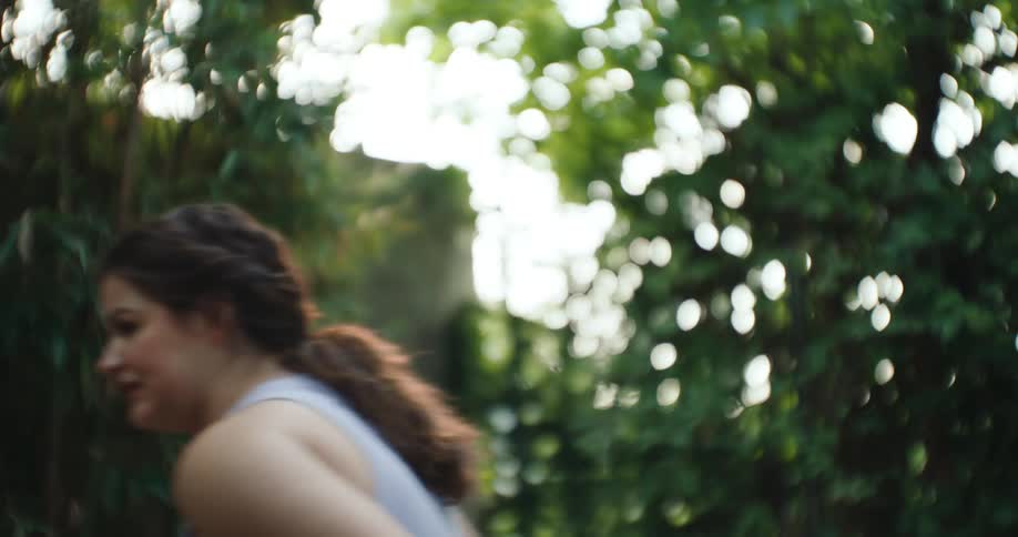 A young female in wheelchair rolls past trees in a garden