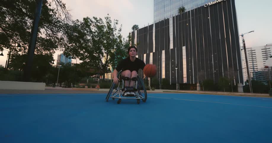 A girl in a wheelchair is playing basketball