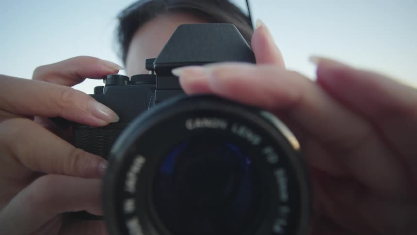 A person is holding a vintage film camera adjusting the lens and taking a picture (POV)