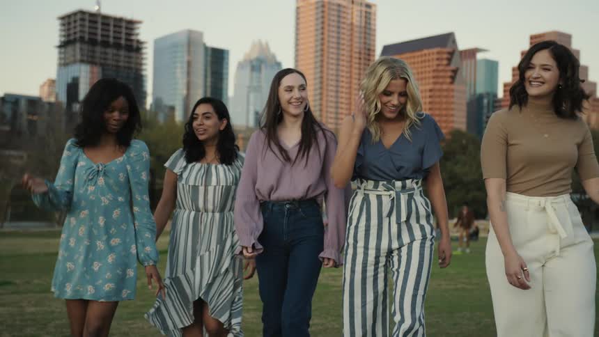 A group of happy friends walks in a city park during late afternoon