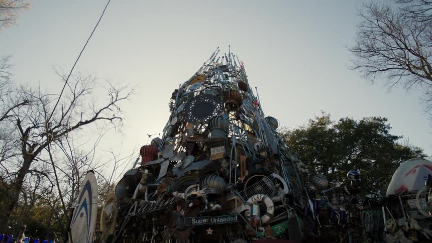 A structure made out of junk sitting in a forest