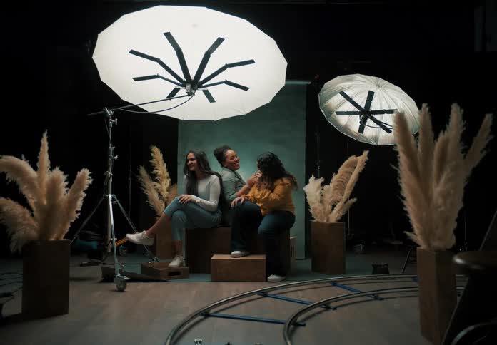 Friends laugh together while sitting for a portrait in a photography studio
