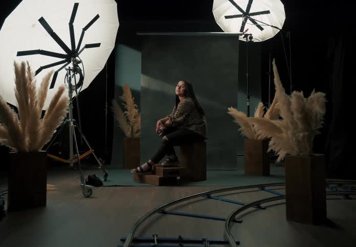 A woman smiles at a camera while sitting in a photography studio