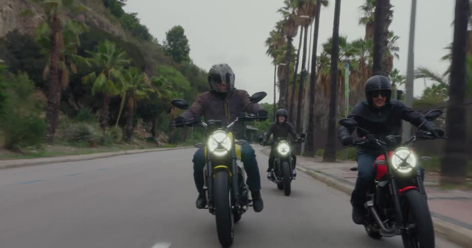 Men are riding motorcycles together down the road