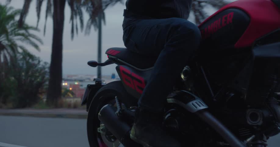 Three people ride motorcycles on a road near a large city