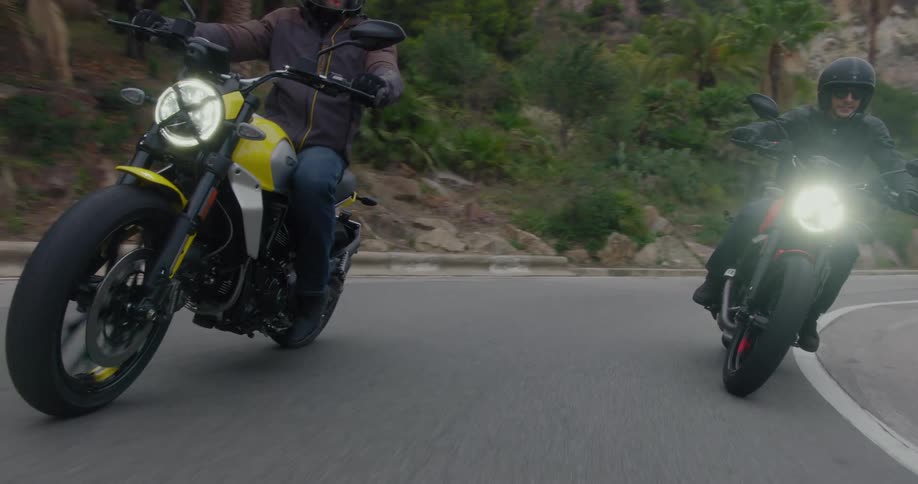 Three bikers riding a motorcycle on an asphalt street and they are making a turn