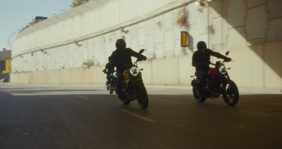 Three people riding motorcycles on the highway under overpasses