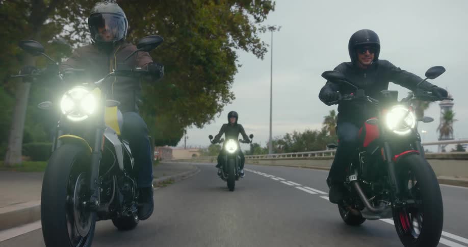 Two men and a woman ride motorcycles down a road