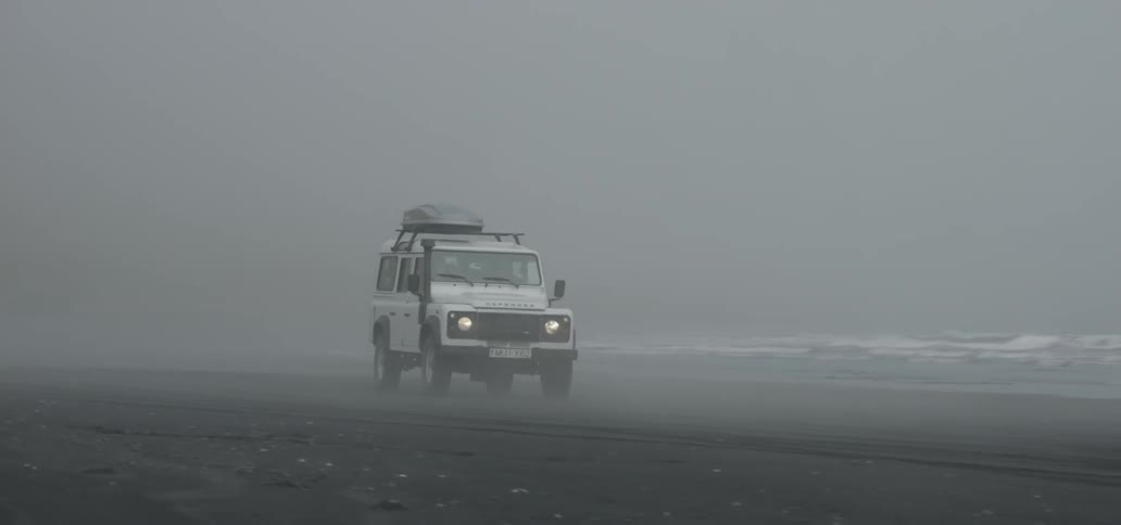 Suv rolling along a beach on a very overcast day
