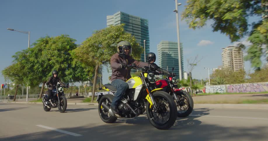 Three bikers riding a motorcycle on an asphalt street in a city
