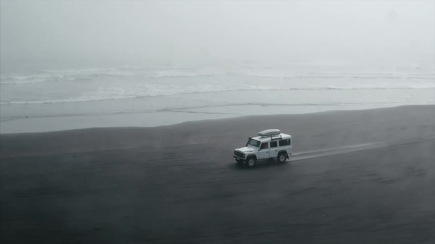 An suv is driving over the sand on a beach