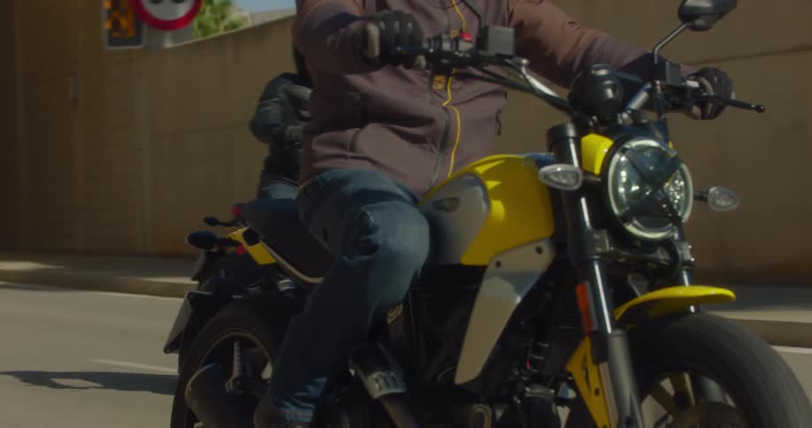 Three bikers on a city freeway coming out of an underpass