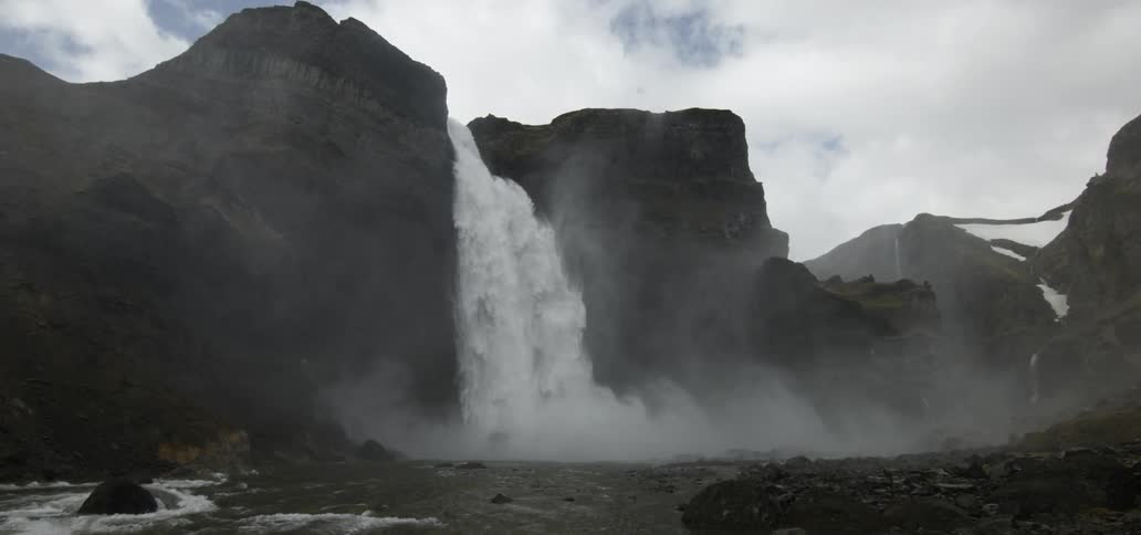 Water plunges off a high cliff to the river below