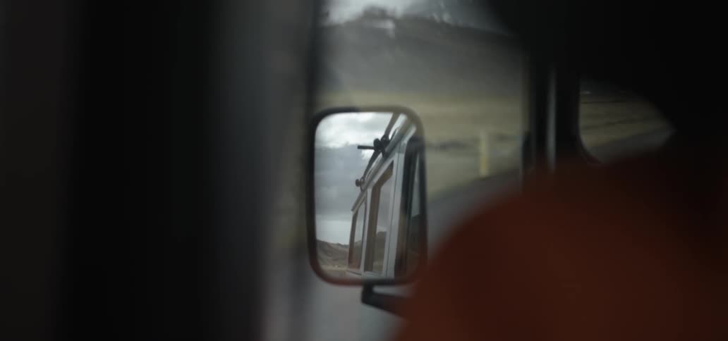 The side mirror of a truck driving down the road