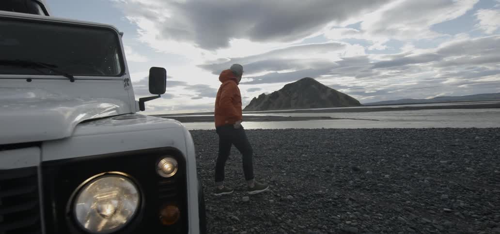 A man exits his truck and walks towards the water