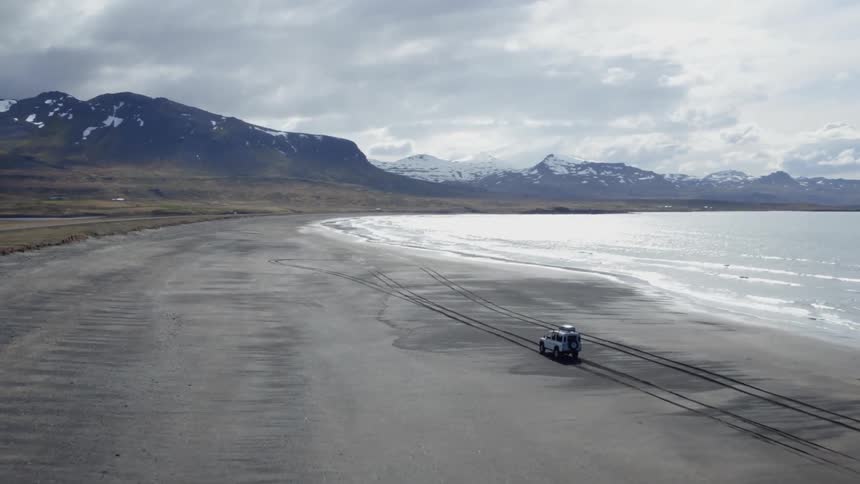 An off road vehicle drives along the beach