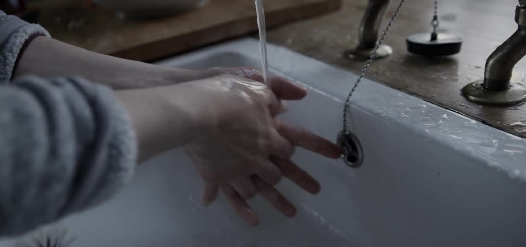 A person washing their hands in a large sink