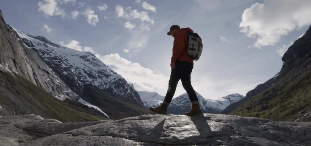 A man hikes in the mountains on a cloudy day