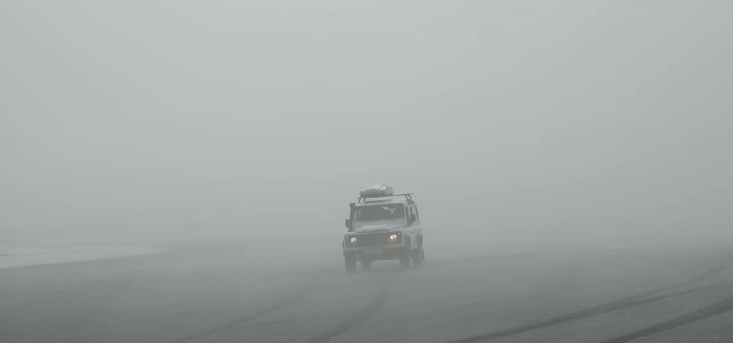A white vehicle turns around in a foggy open area