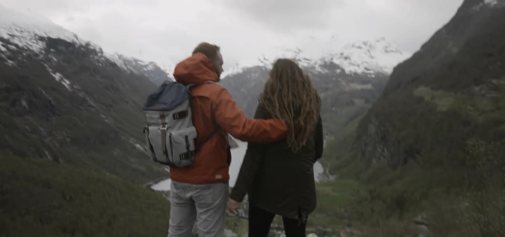 Couple embracing as they look down at the wilderness from high upon some rocks
