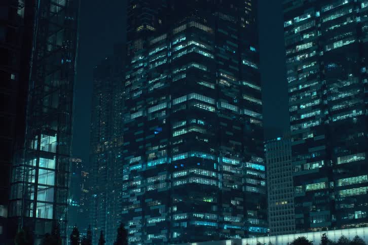 A time lapse of high rise office buildings at night with lights in the windows flickering on and off