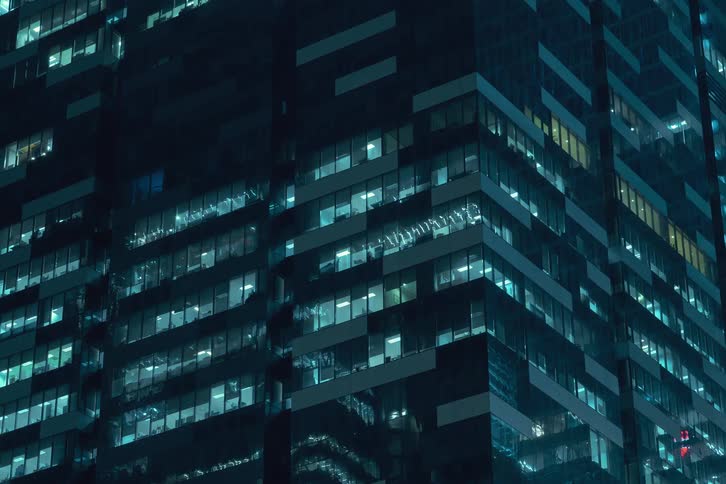 A time lapse of windows lighting up on a skyscraper