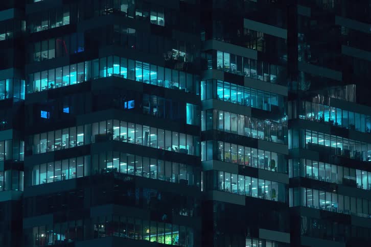 A time lapse of an office building at night with lights in the office windows flickering
