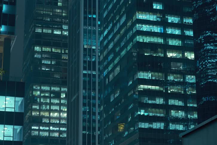 A time lapse of high rise buildings at night with lights in the offices flickering on