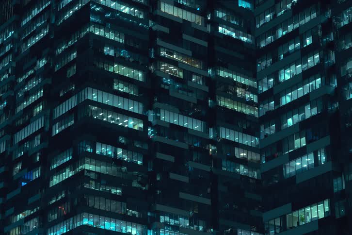 The lights of the apartments in a building turning on as the night goes on