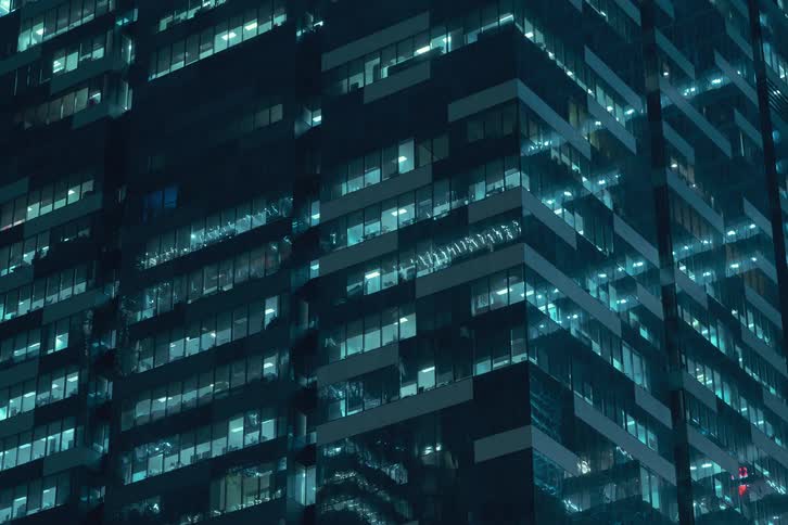 A time lapse of a high rise office building at night with lights in the windows turning on and off