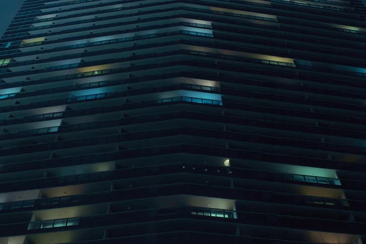 The colorful lights of the apartments in a large building flash and flicker