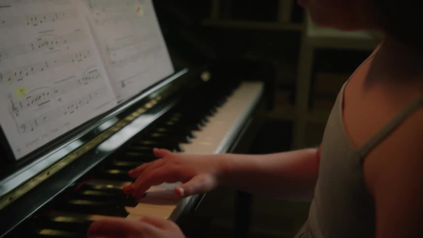 A girl with down syndrome is practicing at a piano with sheet music