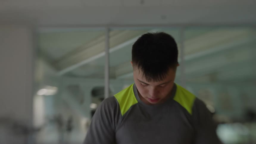 A young man with a gray shirt with yellow details and he looks down