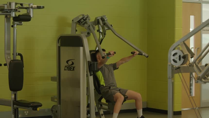 A young man is doing resistance training in a fitness center