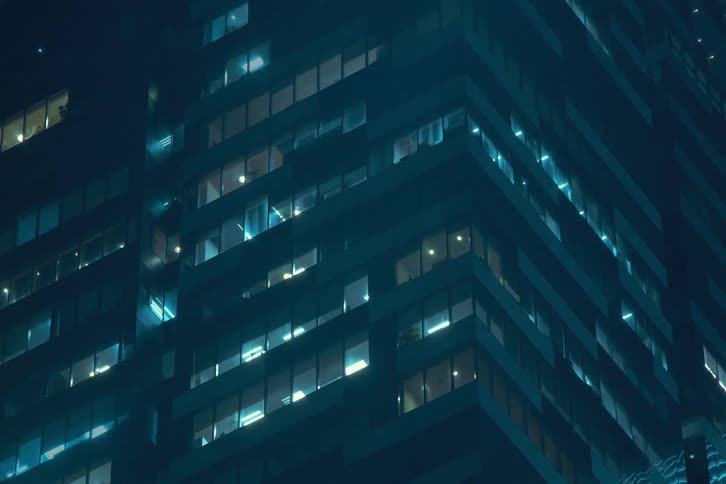 A time lapse of a skyscrapers windows lighting up at night