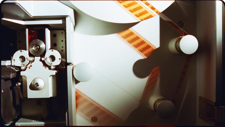 A machine with some pulleys pulling a roll of amber colored film
