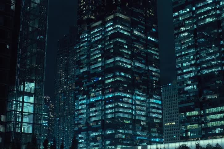 Several buildings light up at night with lights turning on in a time lapse at night