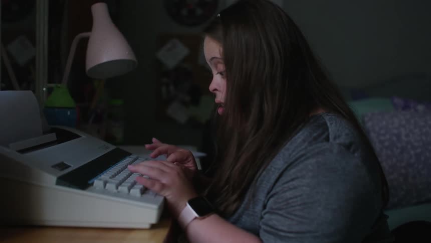 Close up of a young girl sitting at her desk typing on a keyboard