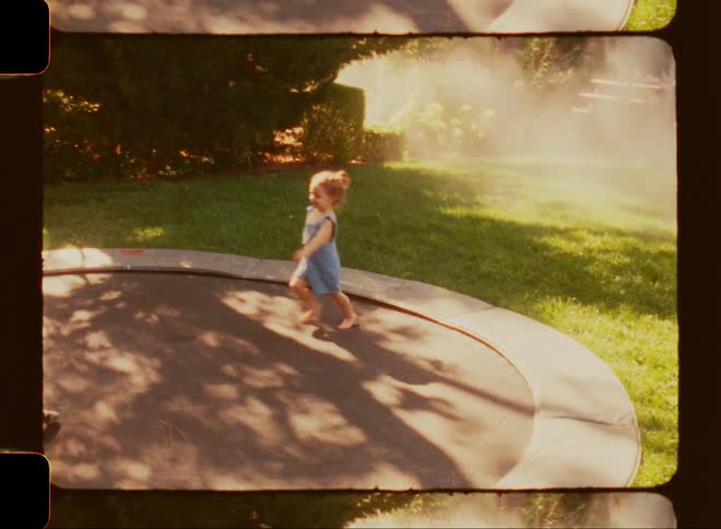 Two children playing on a trampoline in the backyard with sunlight filtering through the trees