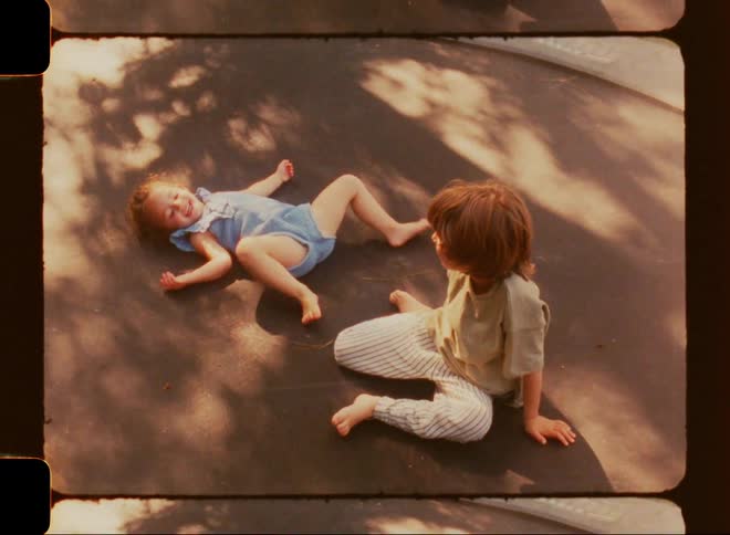 A young boy and girl laying on a trampoline in the middle of a summer day