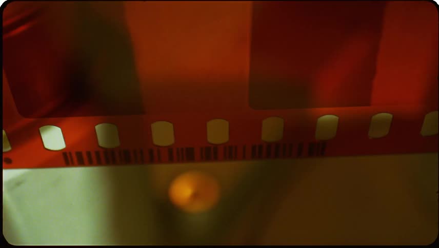 Closeup view of a section of a reddish brown film strip with transparent frames