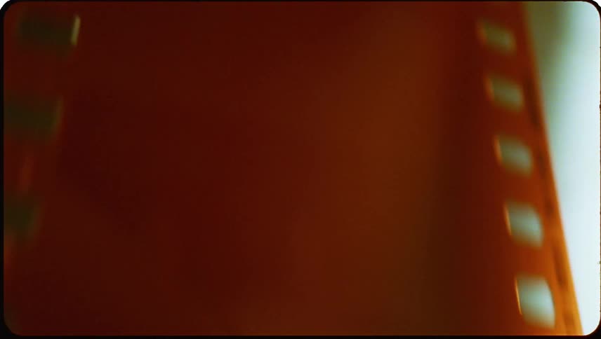 Close up of an orange photography film sliding down and being fed