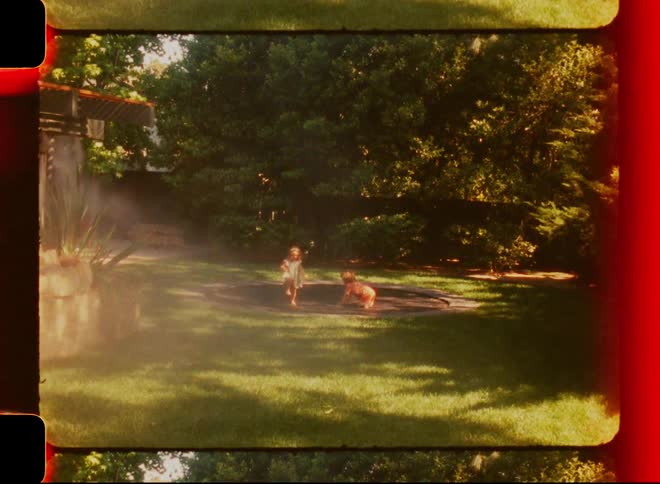Children playing on a trampoline set into the grass in the backyard