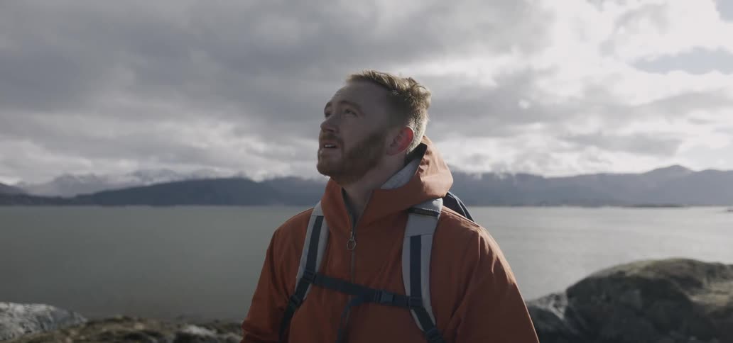A man is standing next to some water looking around at the scenery