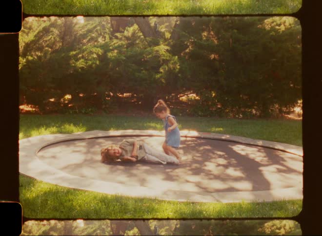 A young brother and sister having fun jumping on a trampoline together in their backyard